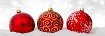 Red Christmas ornaments on snow, festive holiday decor.