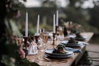 Elegant outdoor dining table setting with candles and floral arrangements in a garden ambience.