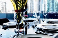 Elegant dining table set with flowers and wine glasses in a modern cityscape restaurant.