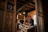 Elegant private chef preparing gourmet dishes in a rustic kitchen setting.