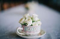 Elegant white roses in a decorated teacup for special events or private chef services in Australia.