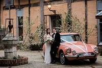 Elegant bride and groom with classic pink car outside vintage venue, wedding celebration, Your Private Chef Sydney Australia.