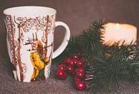 1. Festive holiday mug with Christmas decorations and candle, perfect for seasonal celebrations.