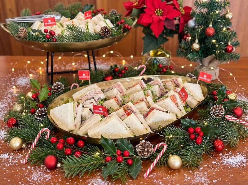 Festive gourmet sandwiches platter with holiday decorations and Christmas theme.