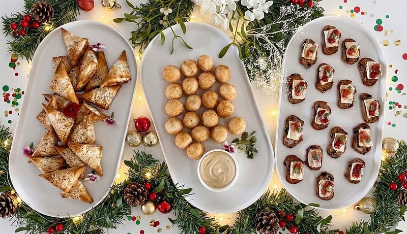 Savory and sweet holiday finger foods, including samosas, coconut balls, and bruschetta, perfect for private chef catering.
