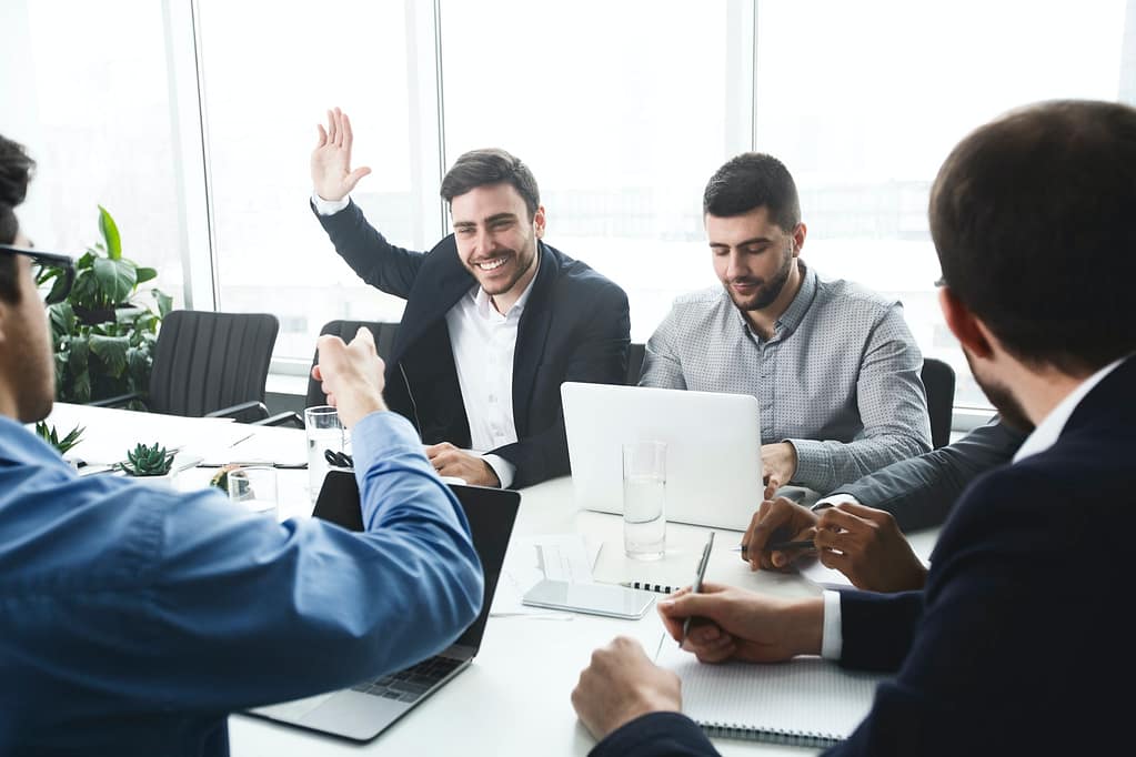 Businessman raising hand and asking question at meeting