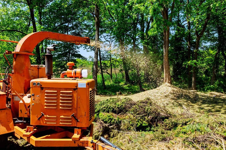 Landscapers using wood Chipper in Action captures a wood chipper or mulcher shooting chips over a